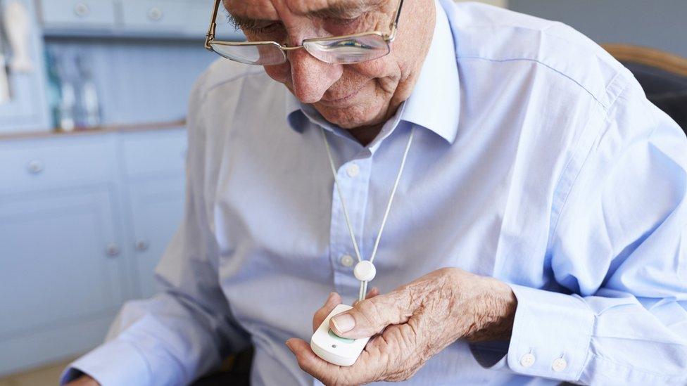 An elderly man uses his pendant alarm