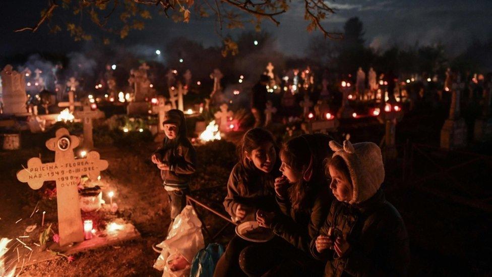 People lit candles and kept vigil at the graves of loved ones during a service in Herasti, Romania.