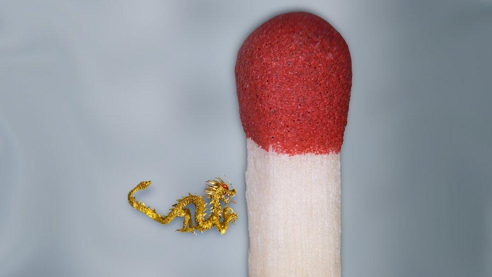 Tiny golden dragon sculpture next to a matchstick