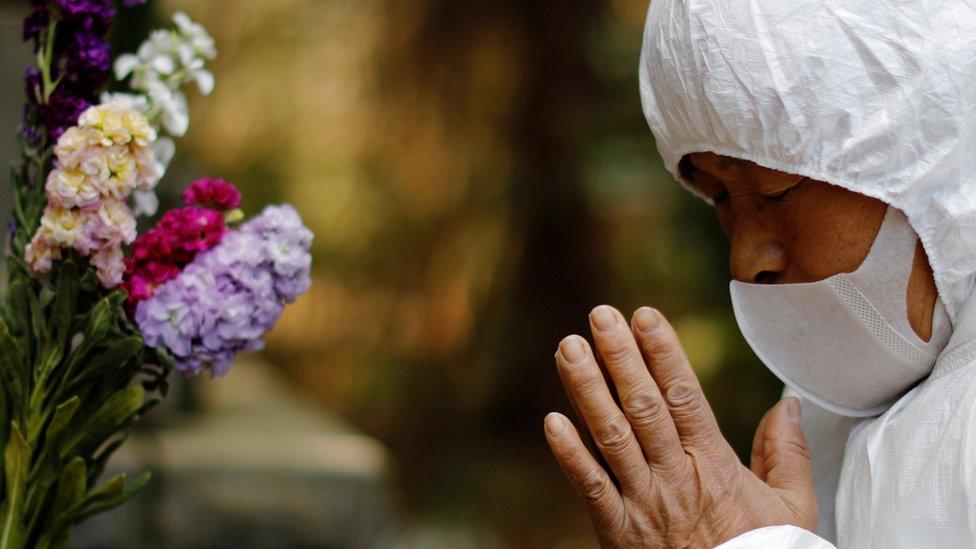 Hisae Unuma wears a protective suit as she prays at her family’s graveyard 2.5km from the power plant, 23 February