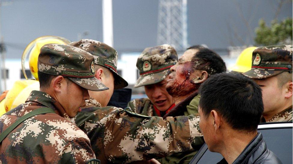 Armed police officers carry an injured man after an explosion at a chemical industrial park