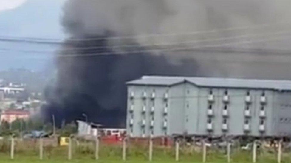 smoke billows from a building in the distance