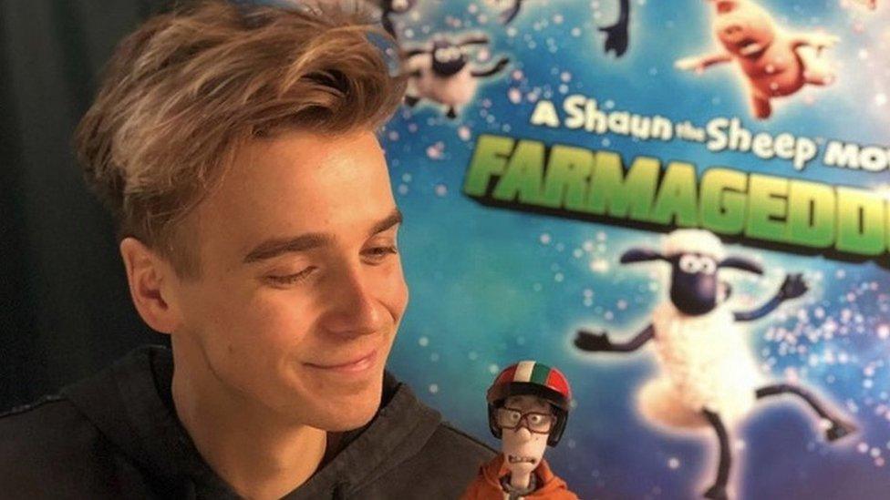 joe sugg holding a doll from sean the sheep