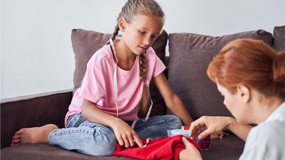 Parent sewing child's clothes