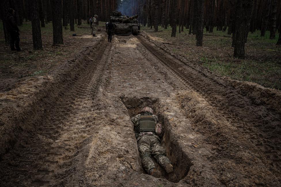 A Ukrainian serviceman lies in a trench during a military exercise in the Kharkiv region of Ukraine