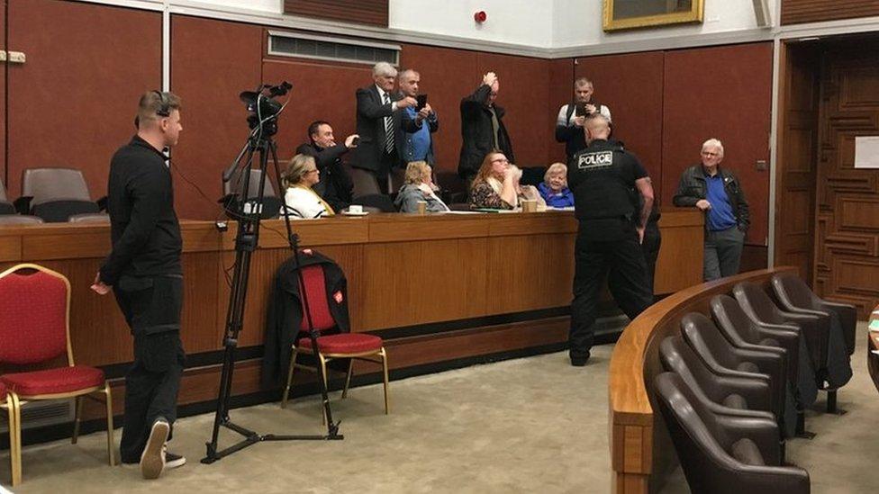 Police officers speaking to members of the public in the gallery of the council chamber