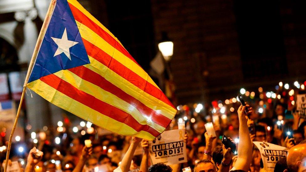 People hold candles during a demonstration in Barcelona against the arrest of two Catalan separatist leaders