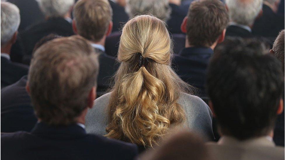 Woman sat in crowd of men