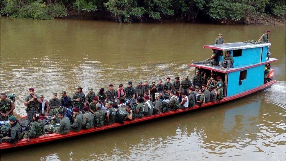 A handout photo provided by the Farc rebels shows them sitting on board a boat in Putumayo province