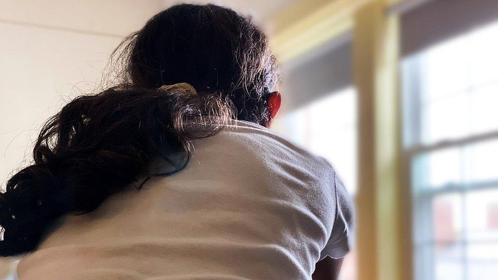 Picture shows the back of an anonymous young persons head and shoulders as they look out of a window