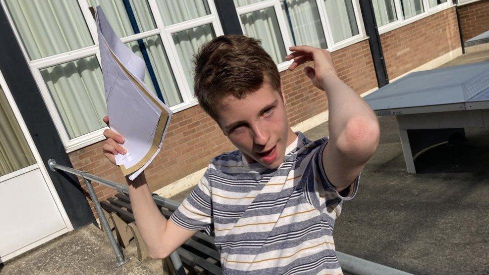 Piers holding up his results while posing with his arm raised