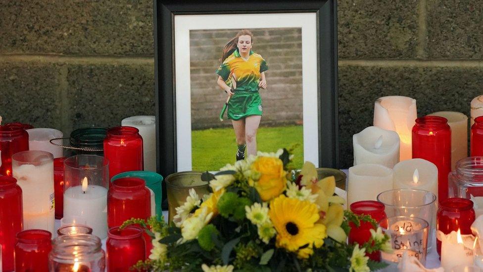 Floral tributes and candles surround a photograph at Kilcormac Killoughey GAA Club, for Ashling Murphy