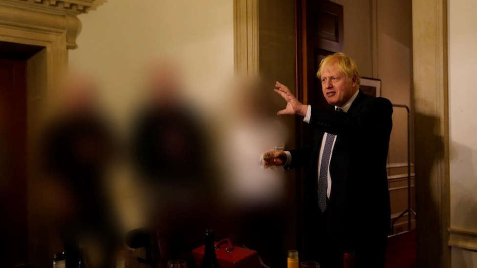 Boris Johnson holding glass of wine in Downing Street on 13 November 2020, others blurred out