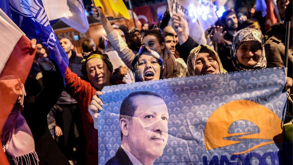 Supporters of Turkey's Justice and Development Party (AKP) wave party flags and hold a flag with a portrait of Turkish President Recep Tayyip Erdogan in Istanbul