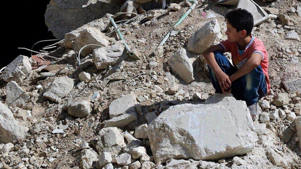 In this picture taken on 11 October 2016, provided by the Syrian Civil Defense group known as the White Helmets, a boy sits amongst rubble in rebel-held eastern Aleppo, Syria