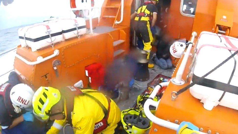 RNLI volunteers attending to people on the floor of the boat