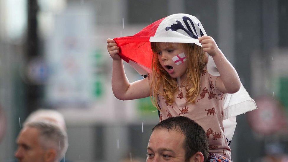 Young England fan carried into the ground using her England flag as a hood.