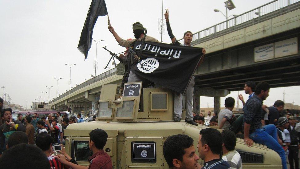 In this Sunday, March 30, 2014, file photo, Islamic State group militants hold up their flag as they patrol in a commandeered Iraqi military vehicle in Fallujah, 40 miles (65 kilometers) west of Baghdad, Iraq.