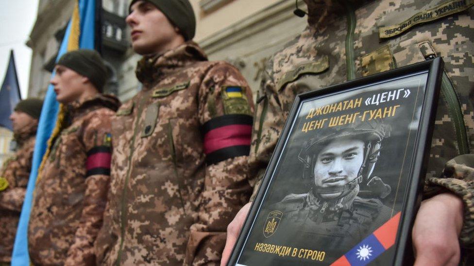 A soldier holds a photo of Tseng Sheng-guang at a memorial service