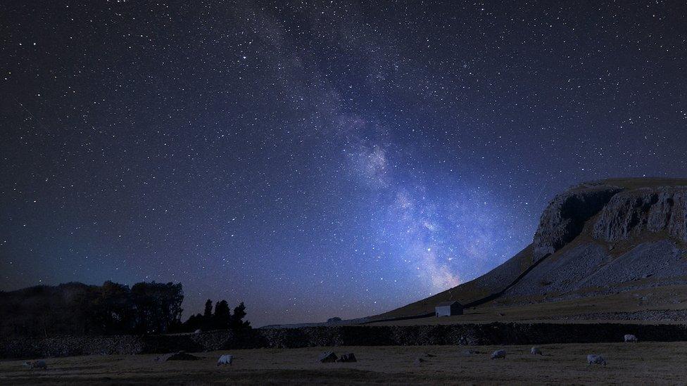 Vibrant Milky Way over the landscape of Norber Ridge and stone barn in the Yorkshire Dales National Park