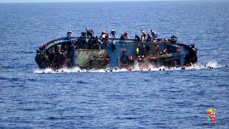 People try to jump in the water right before their boat overturns off the Libyan coast on 25 May