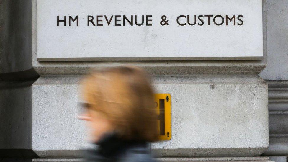 A woman walks in front of the HMRC building sign in Whitehall