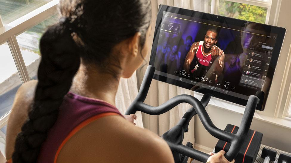 A woman using a Peloton bike