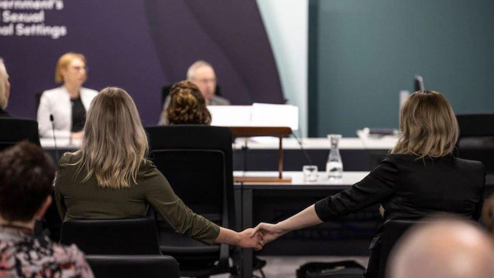 Tiffany Skeggs holds hands with a friend during the inquiry