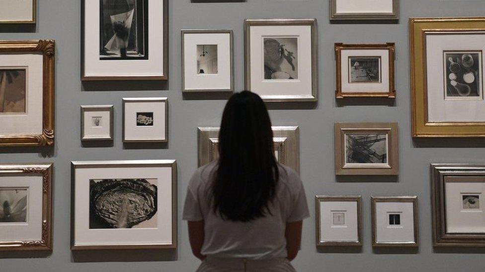 A member of staff poses in front of photographs belonging to Elton John during a press preview for The Radical Eye: Modernist Photography from The Sir Elton John Collection at Tate Modern