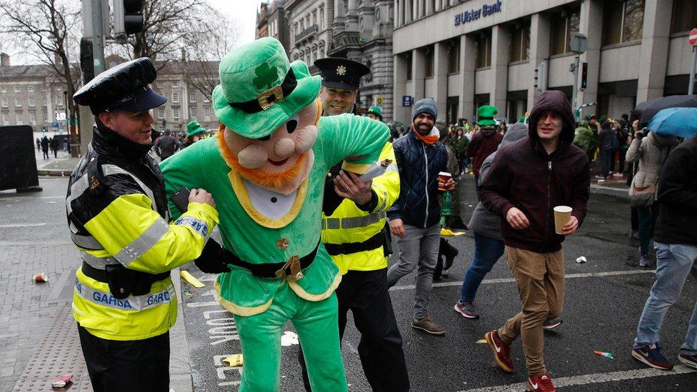 Police officers pretend to arrest a man dressed in a leprechaun outfit in Dublin