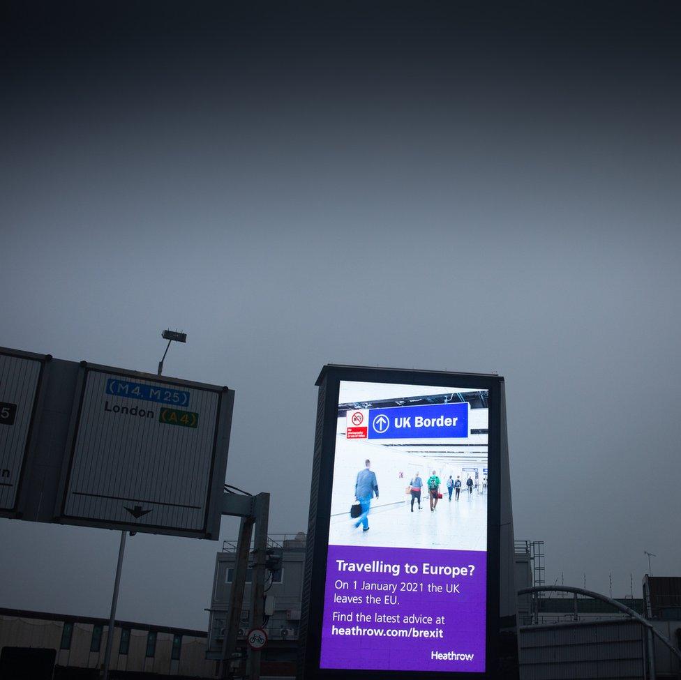 An image of a motorway sign next to a sign giving people Covid travel instructions