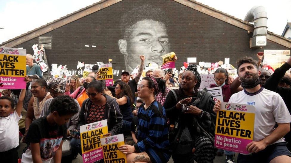 Protestors in front of the Marcus Rashford mural