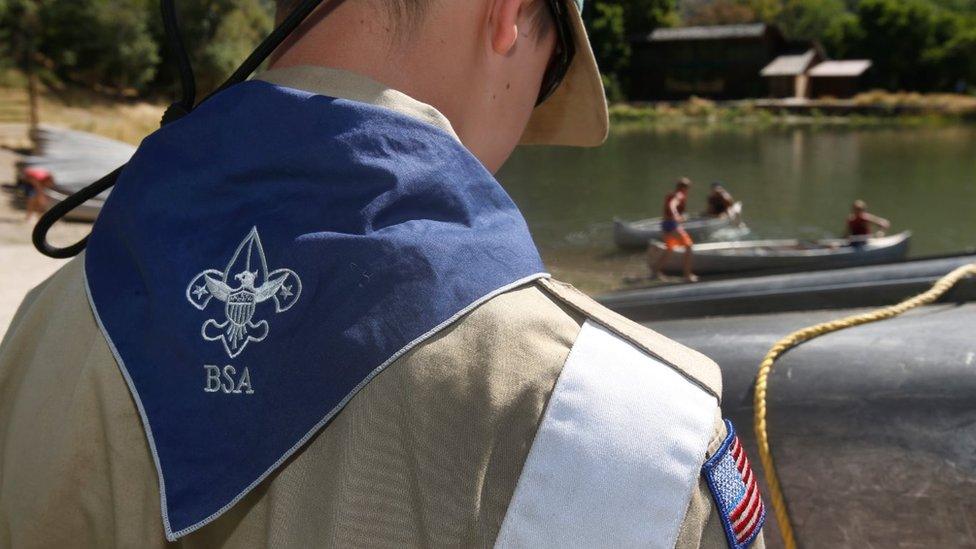 A Boy Scout of America stands with his back to the camera