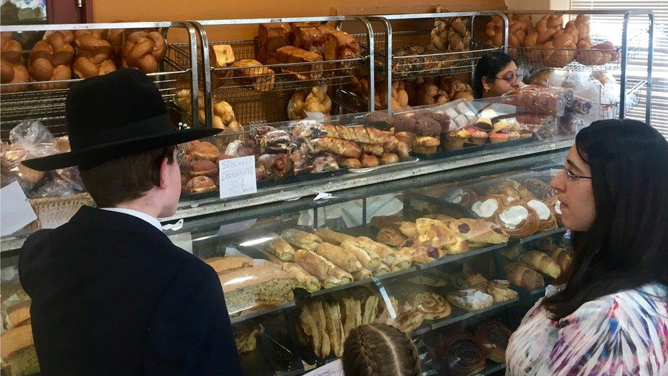 Two customers inside a bakery that has various breads and sweet pastries on display