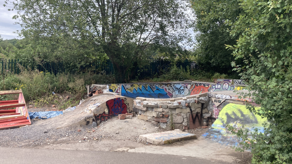 A small 'bowl' area used for skateboarding with graffiti on the sides