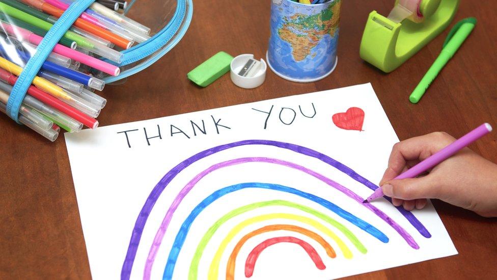 A hand drawn sign of a rainbow, red heart and the words thank you