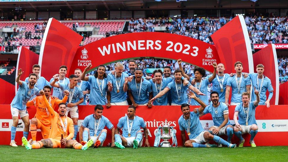 A full team picture of Manchester City underneath a banner that reads 'WINNERS 20203'