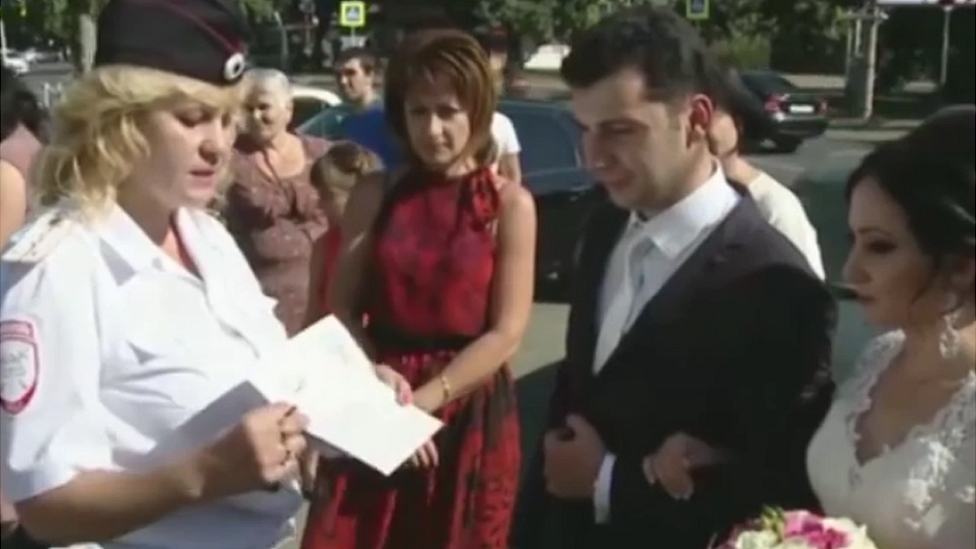 A policewoman presenting a couple with a card with instructions for their wedding day