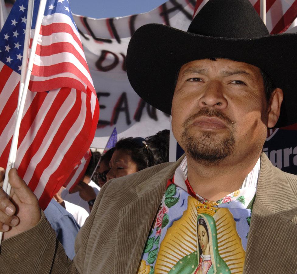 Juan Galvan holds a U.S. flag as he participates in the Mega March on City Hall April 9, 2006 in Dallas, Texas