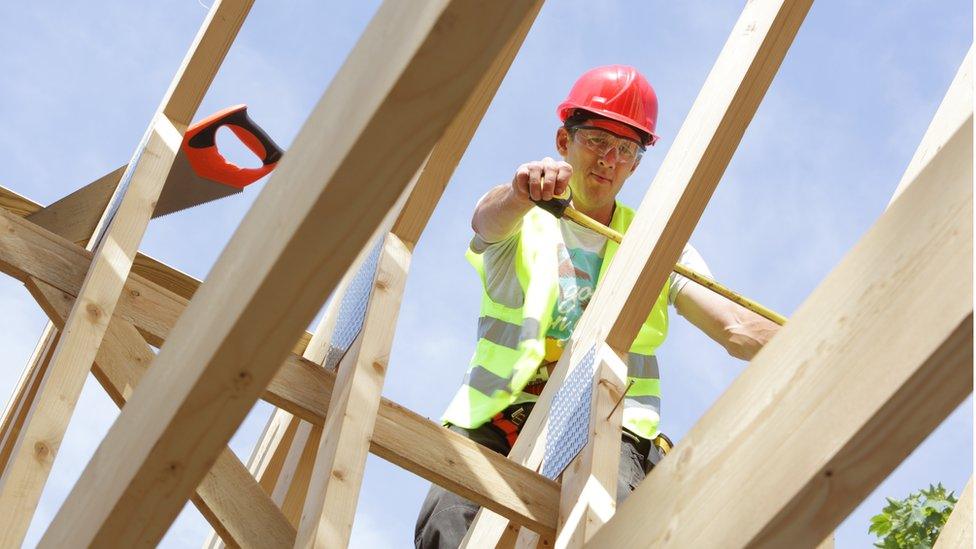 Builder working on roof of house - stock photo