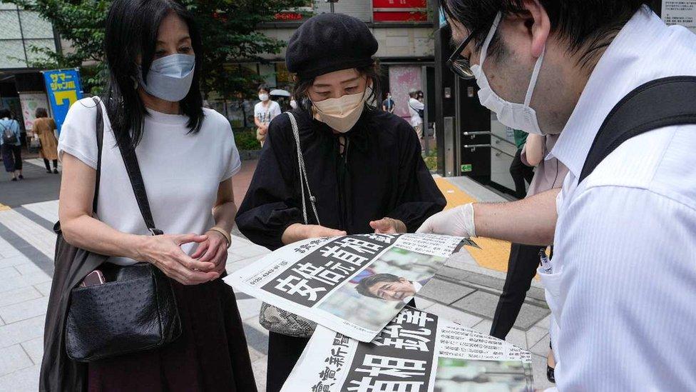 Women and man looking at newspaper report