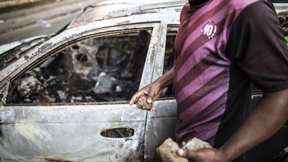 A protester holds stones in his hands as he walks past a barricade adjacent to the national Assembly in Libreville on September 1, 2016