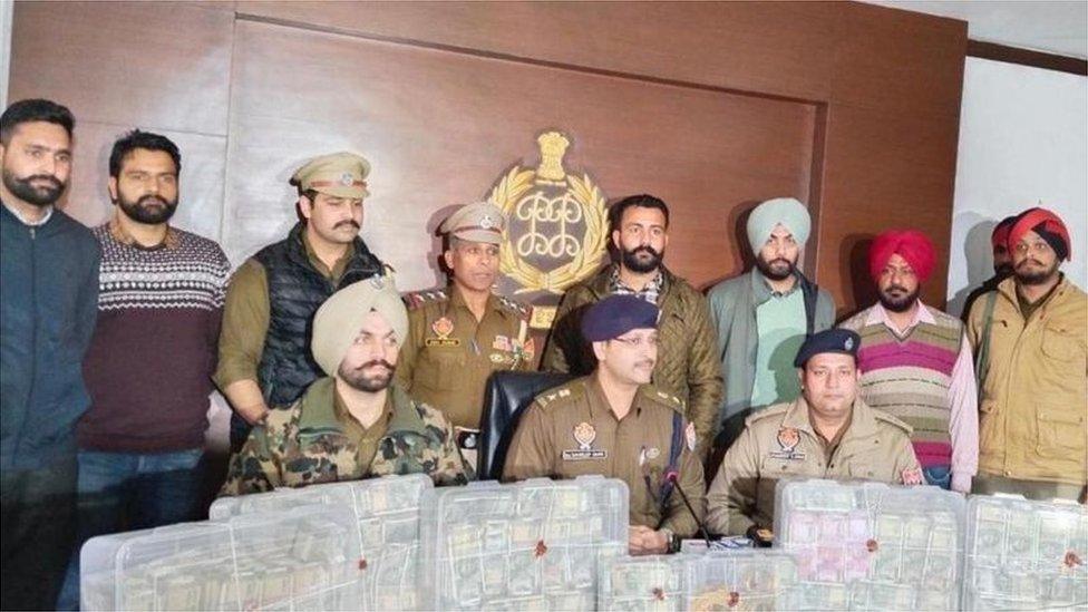 Punjab police with the money seized from a gang member's home in Punjab