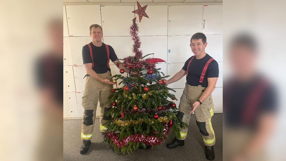 Two fire fighters with a Christmas tree