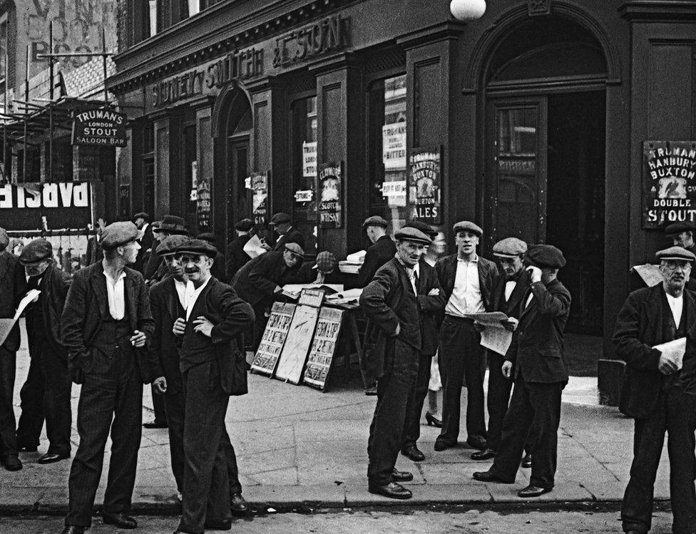 Working men gather outside a public house in Canning Town, London, 1935