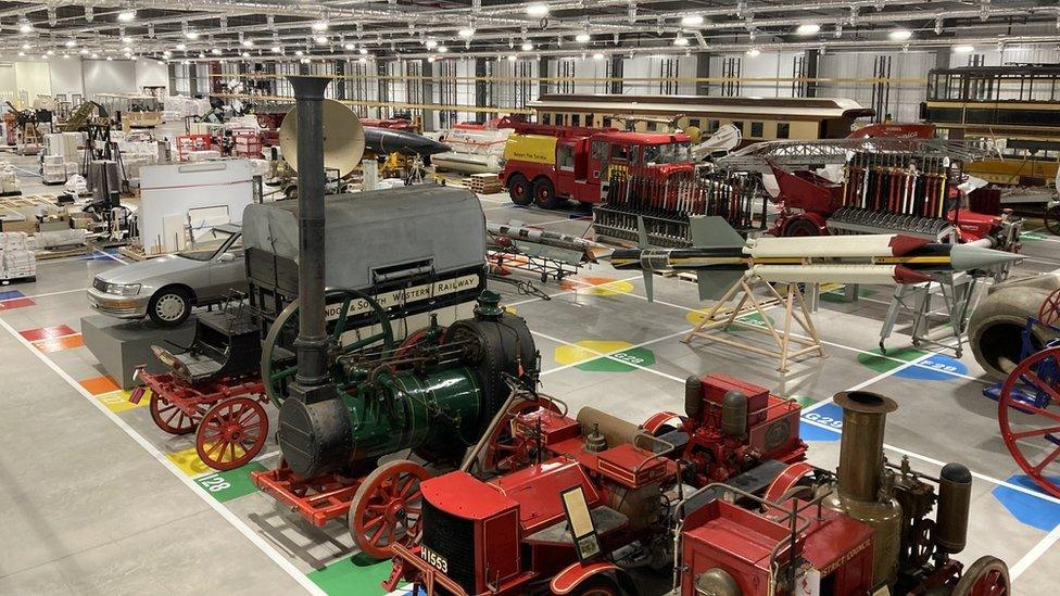 A building that looks like a warehouse with old and vintage vehicles