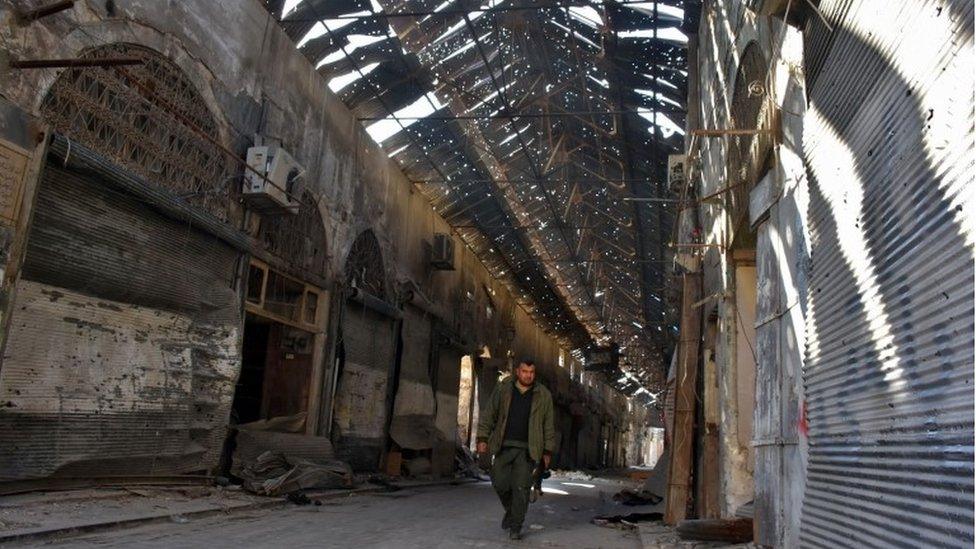 A Syrian pro-government fighter walks past closed shops in the Bab al-Nasr district of Aleppo"s Old City on 9 December 2016