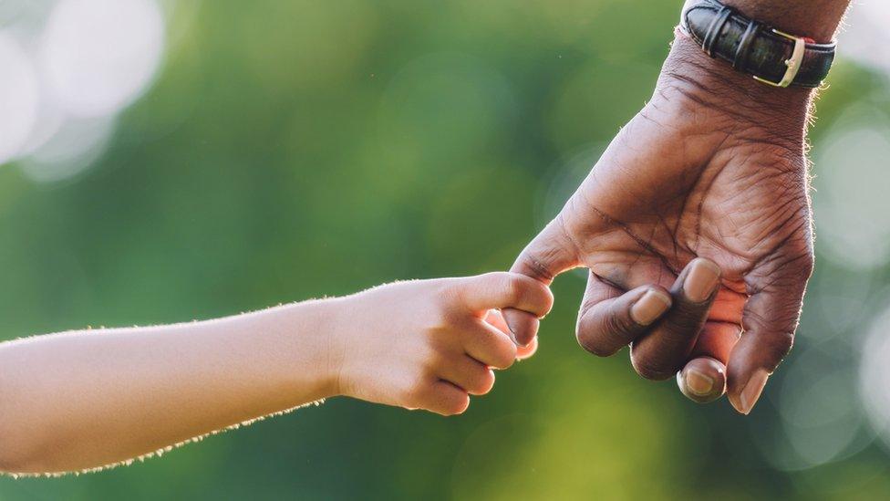 Child holding adult's hand - posed