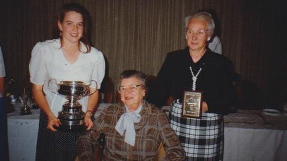 Women holding sporting trophy