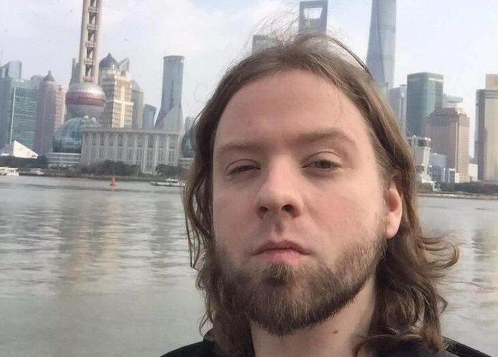 Naaman Kisby standing in front of a waterfront with a number of high rise buildings behind him